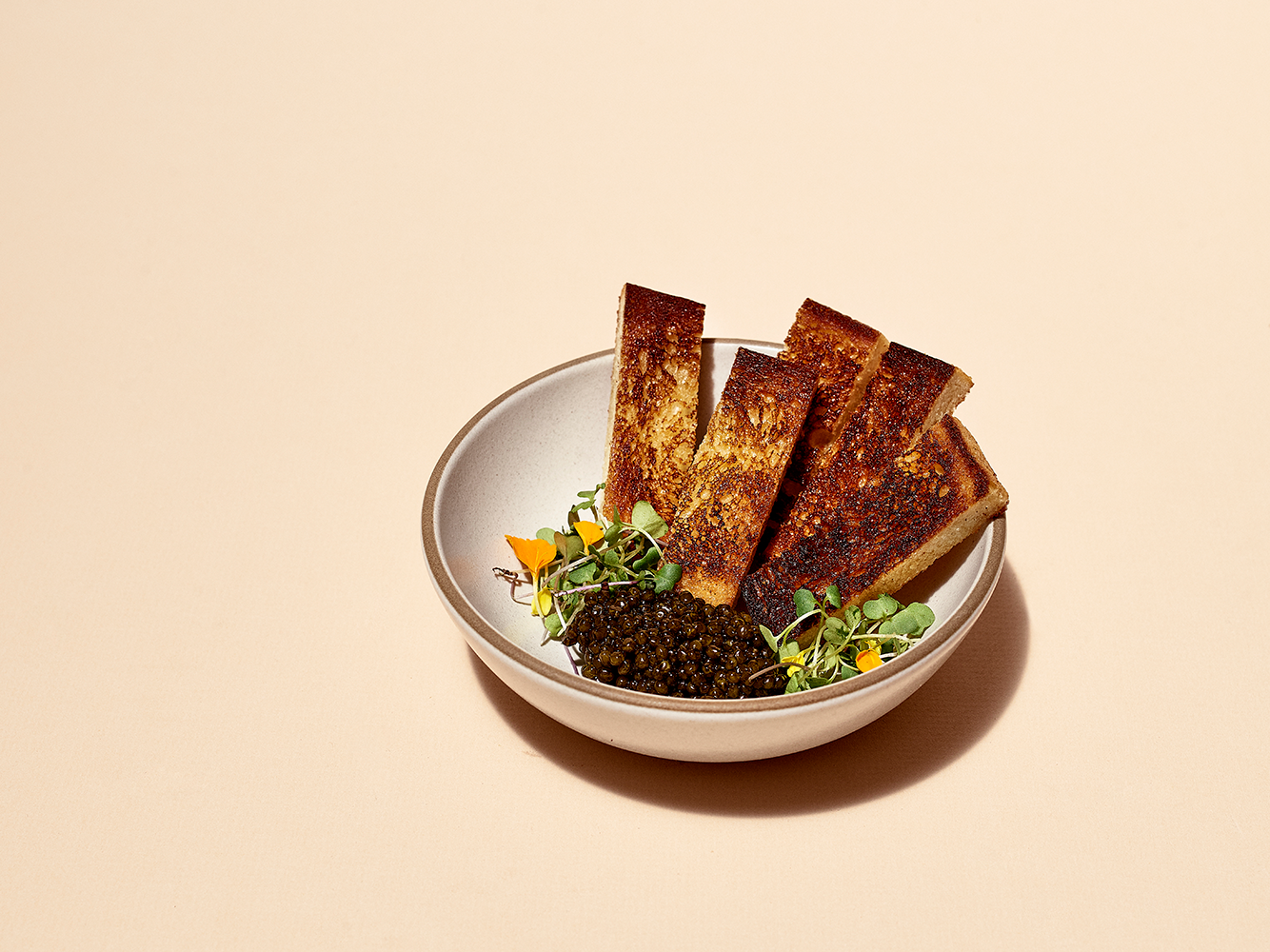 a bowl of food with toast and caviar on a table