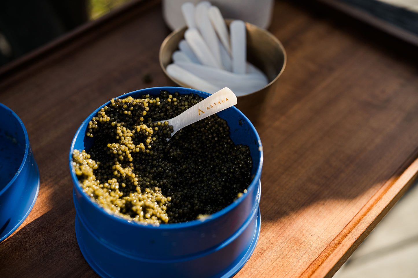 a party-sized tin of caviar sitting on a brown serving board