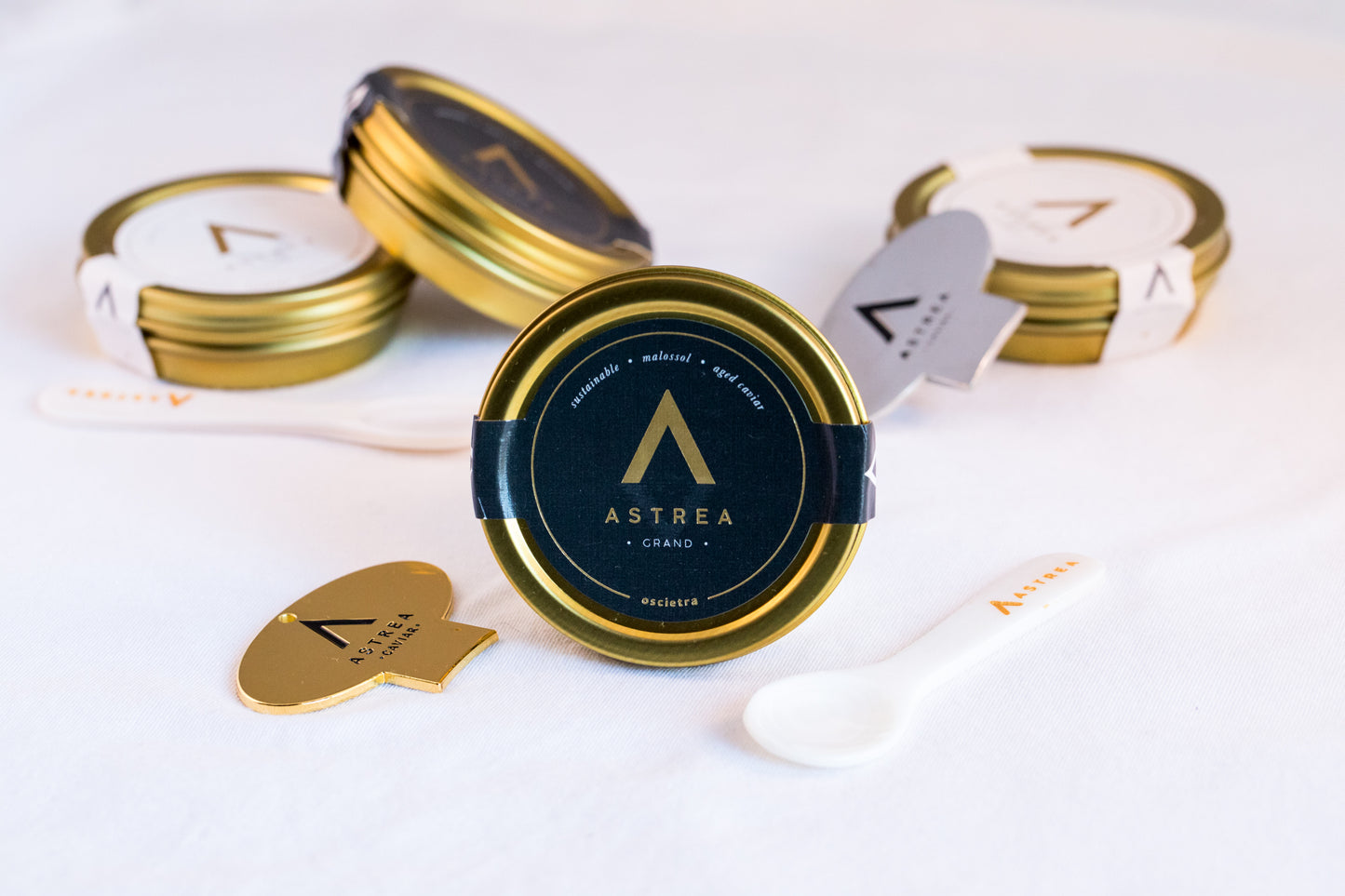 a tin of astrea kaluga oscietra caviar with a tin opener and serving spoon