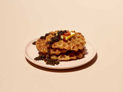 a stack of waffles with butter and syrup on a pink plate