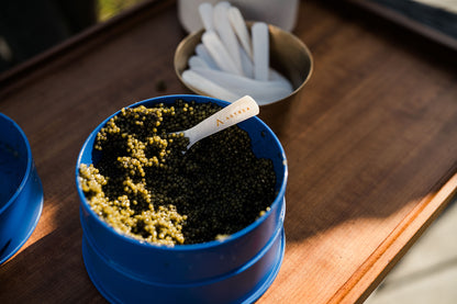 a party-sized tin of caviar sitting on a brown serving board