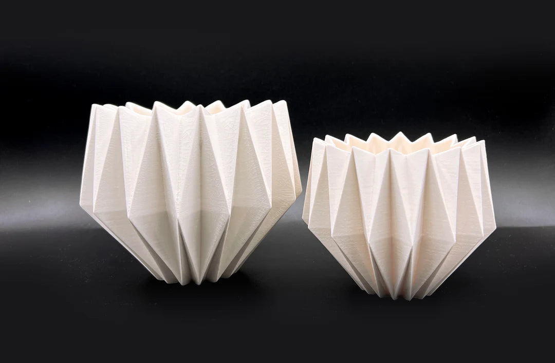 two white origami bowls on a black surface