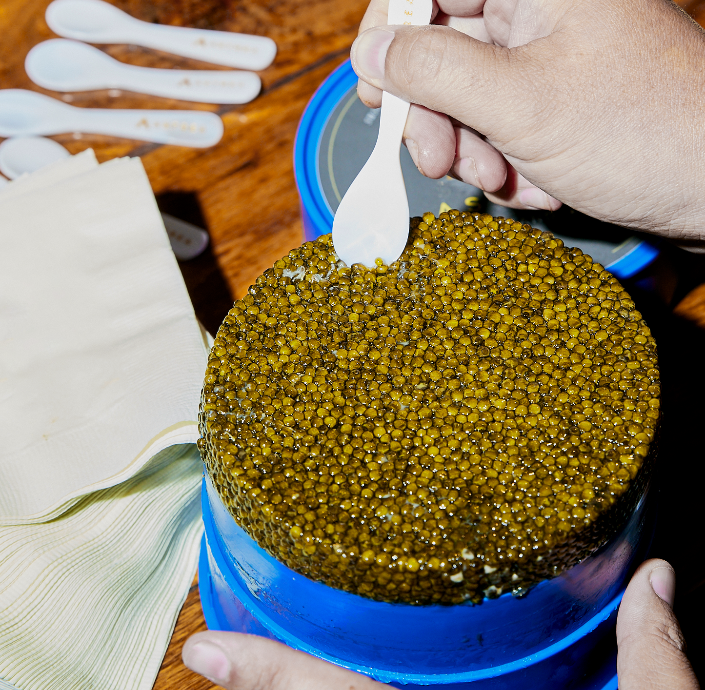 a person scooping caviar out of a blue container