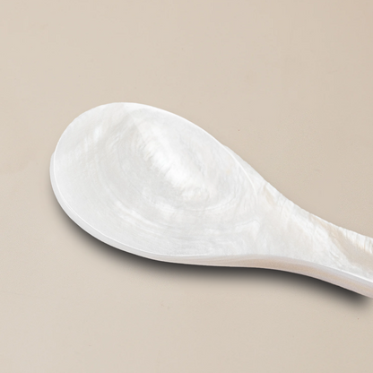 a white spoon sitting on a beige surface