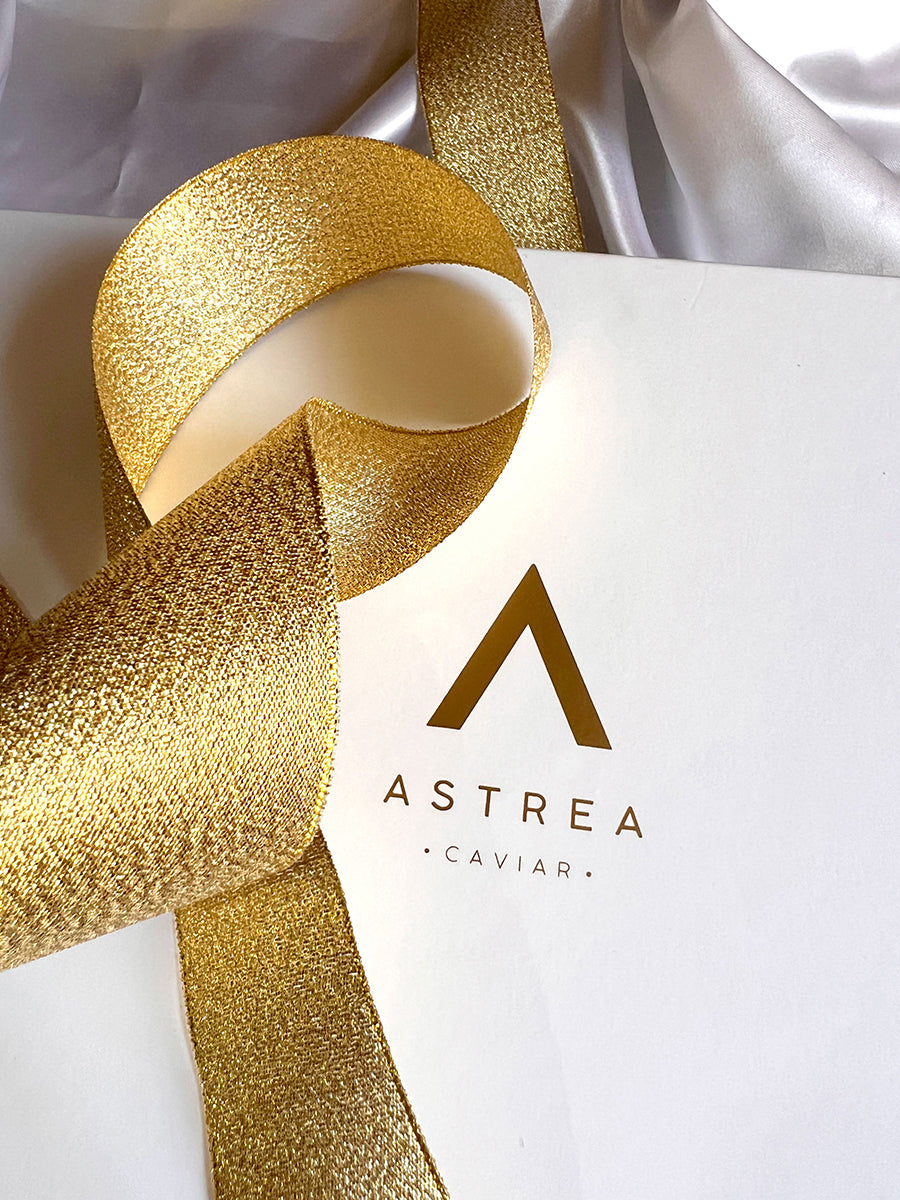 a white box with a gold ribbon that says astrea caviar
