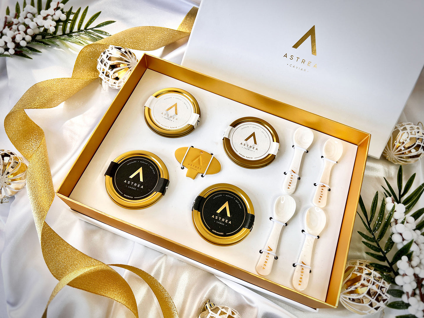 a gift box set of astrea caviar including four jars of caviar is on a white table
