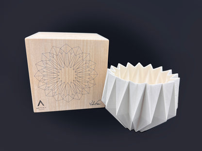 a white oragami bowl sits next to a box that says Astrea on it