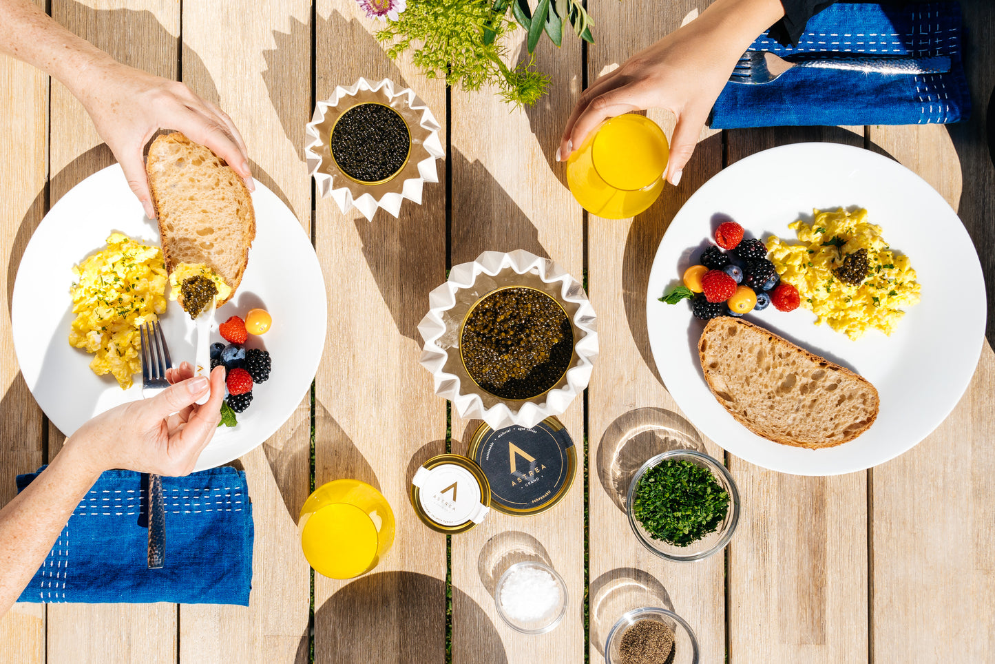 two people are sitting at a table with plates of food and caviar